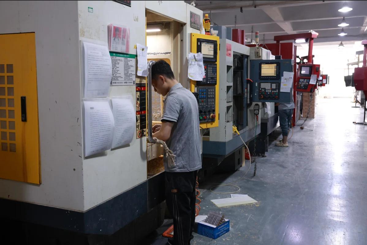 CNC machining operator working with production equipment in a Chinese factory